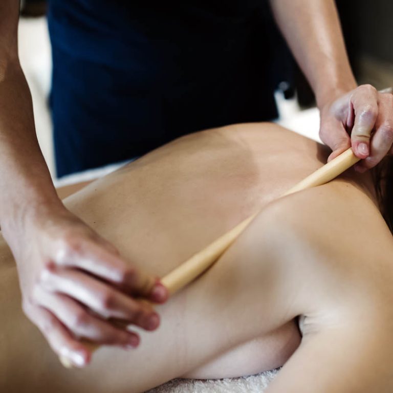 Masseur using massage bamboo sticks during treatment