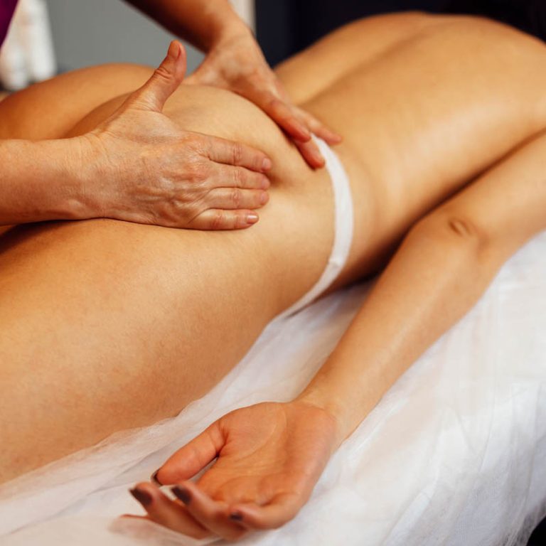 Masseuse makes anti cellulite massage of buttocks, thighs and legs to her client. Slimming and body shaping in spa salon. Relaxing treatment. Free space for text.