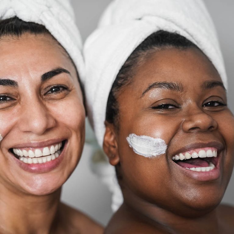 Multiracial senior and young women doing beauty treatment using skin masks - Body care concept - Focus on african woman eye