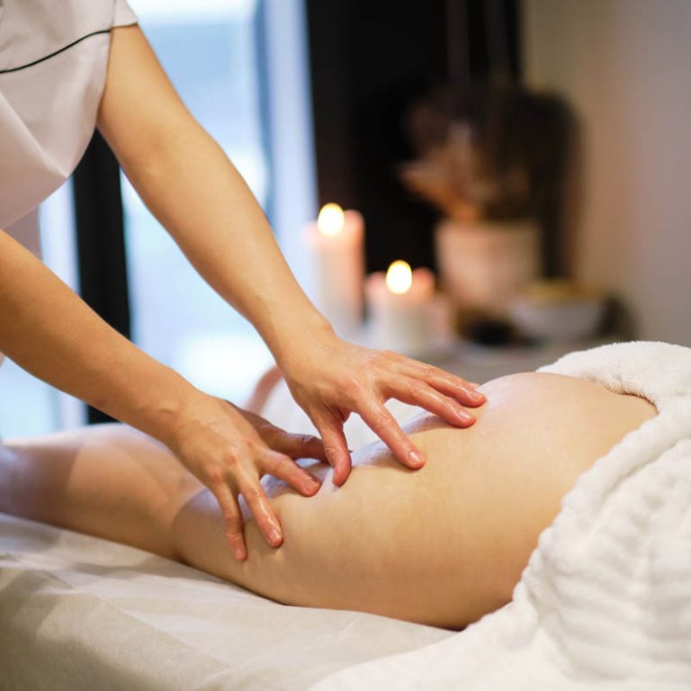 Professional masseuse performing a soothing cellulite reduction massage on a female client