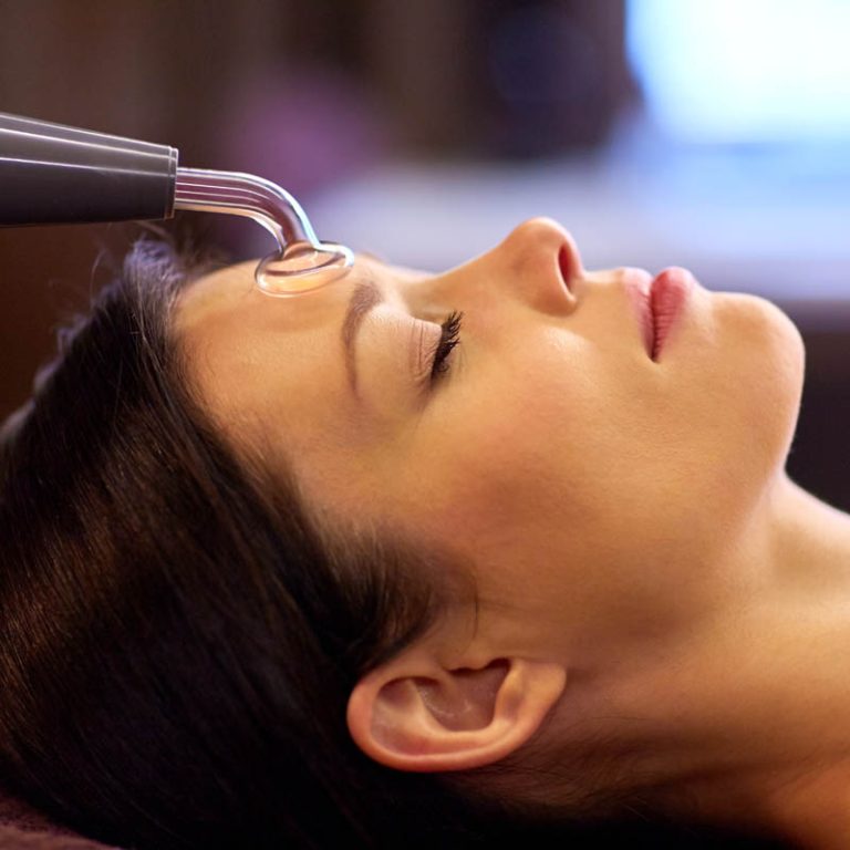 people, beauty, cosmetology and technology concept - beautiful young woman having needle free mesotherapy or hydradermie facial treatment by microcurrent firming device in spa